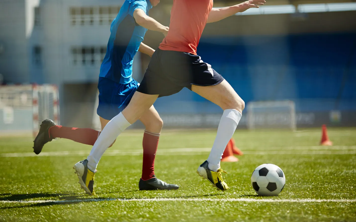 Two footballers contesting the ball on a grass pitch
